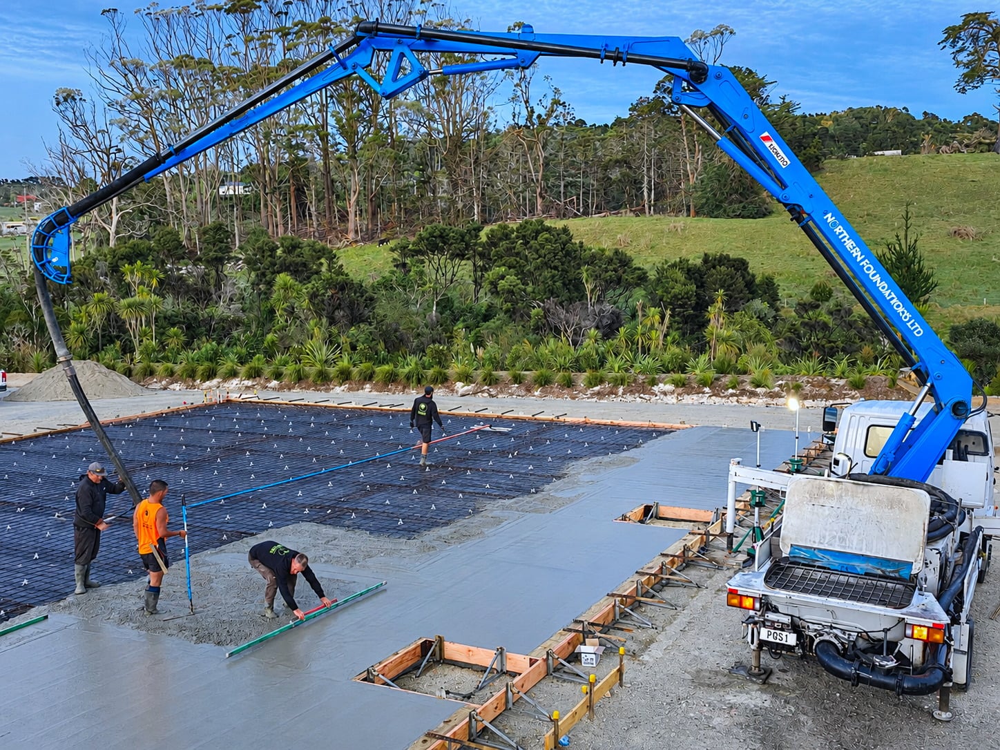 The boom pump placing concrete while the crew screeds the slab