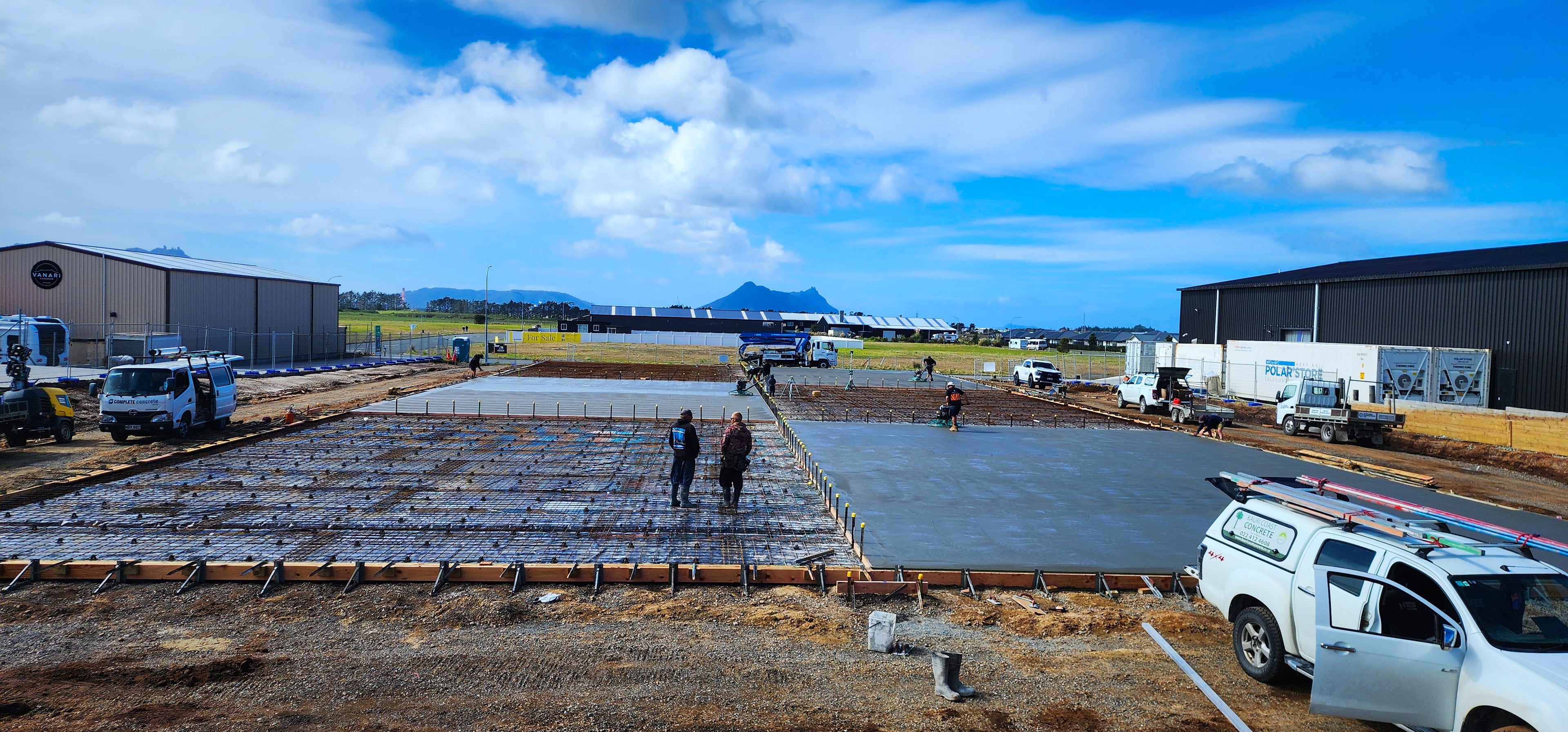 A large slab mid-pour beside commercial buildings, with a ute in the foreground